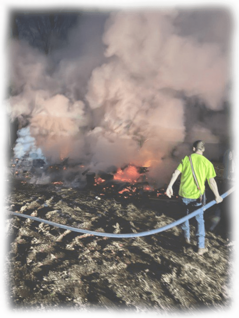Firefighters battle a large blaze engulfing a structure at night.