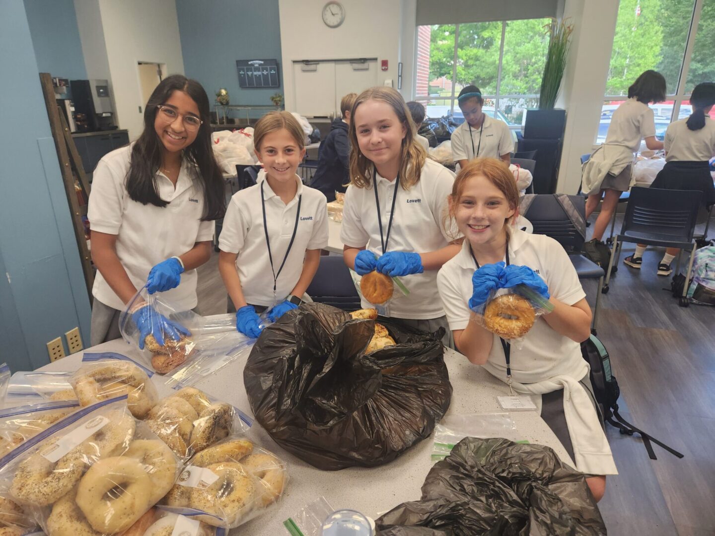 Children in a classroom preparing food with gloves and smiles.