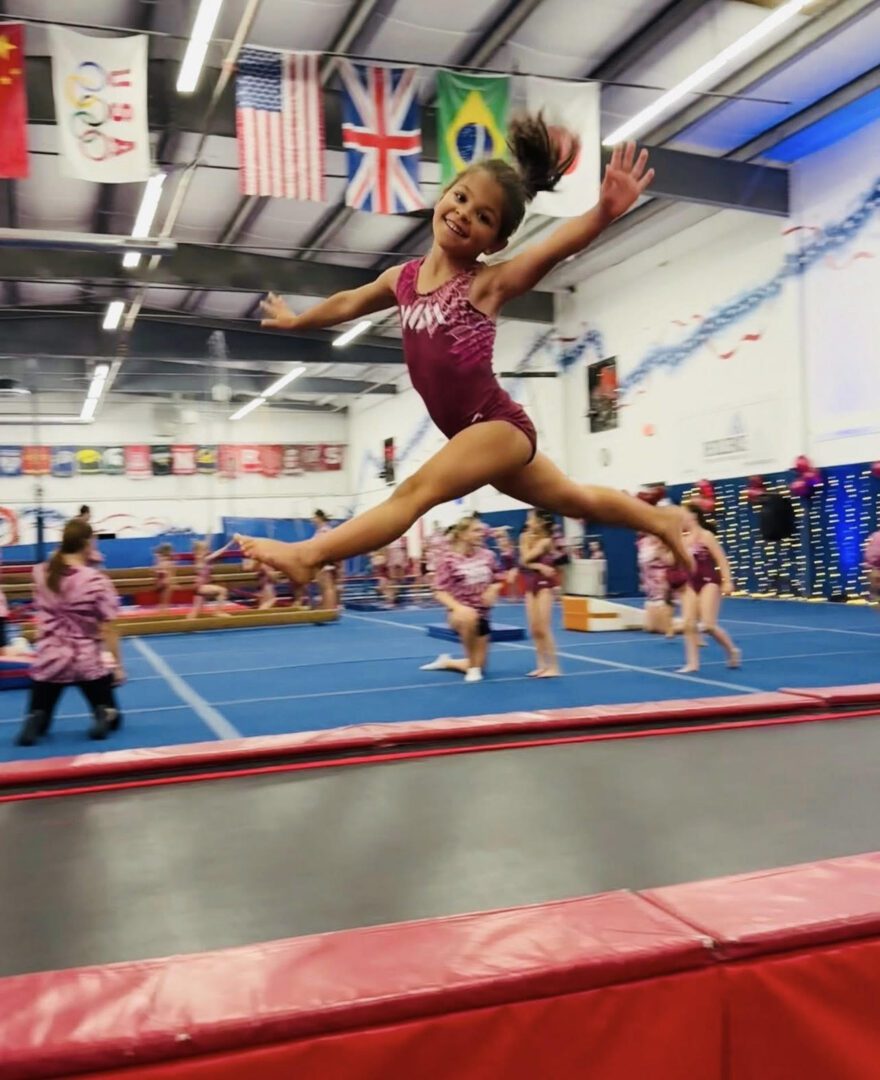 Young gymnast leaps gracefully in a colorful gym.