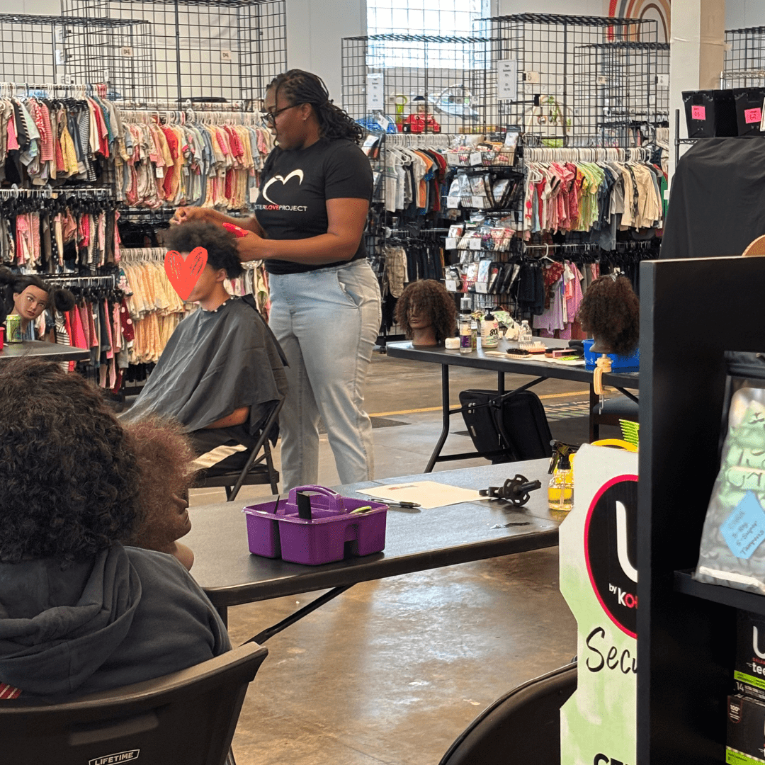 People getting haircuts in a busy salon with colorful products on display.