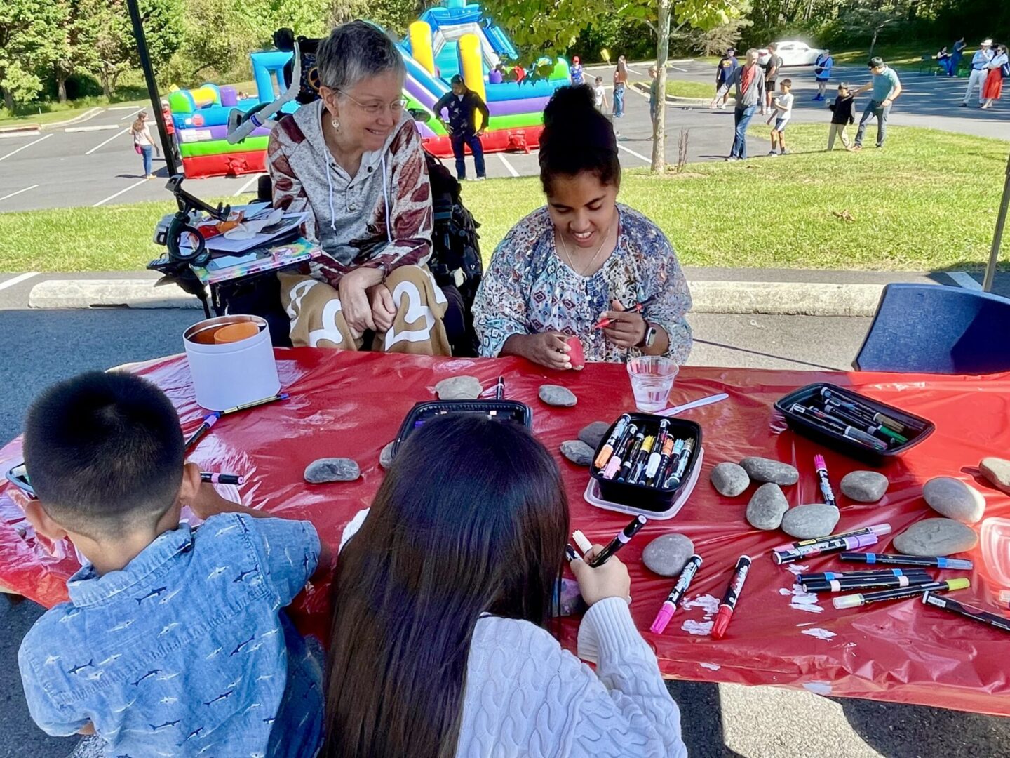 People enjoying a pottery painting activity outdoors under a tent.