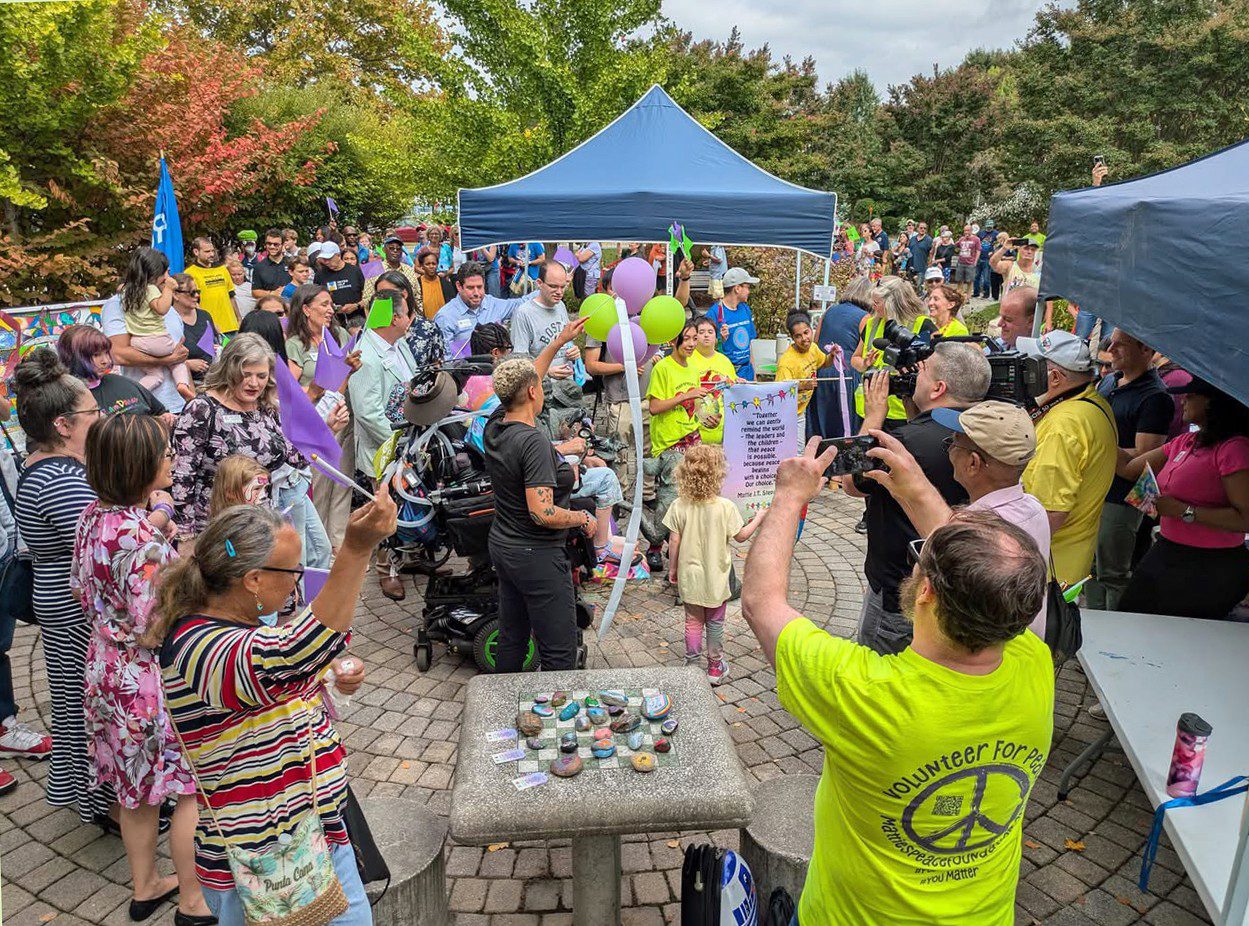 Community event with people gathered around a table and colorful balloons.