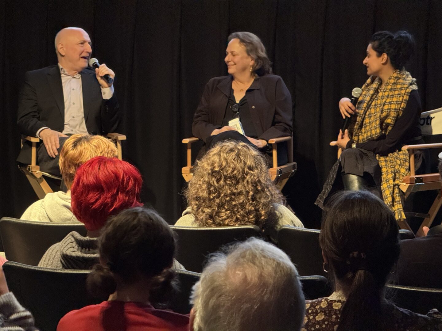 Panel discussion with three speakers addressing an audience in an intimate setting.